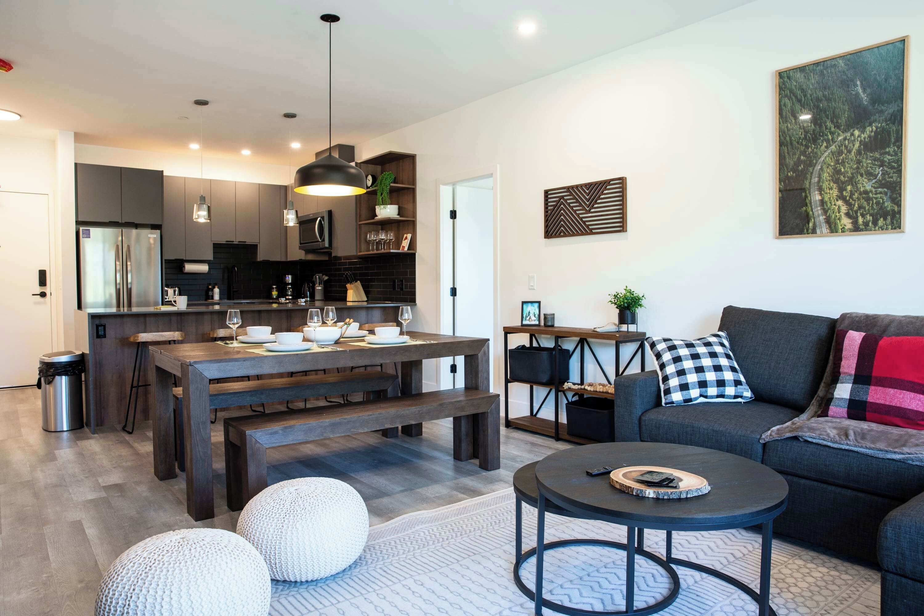 A modern kitchen with dark cabinetry, a central island, and pendant lighting.
