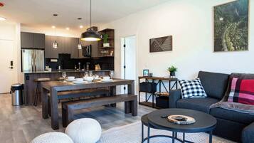 A modern kitchen with dark cabinetry, a central island, and pendant lighting.