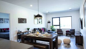 Una sala de estar moderna con una mesa de comedor, sofá, sillas y un ventanal grande.