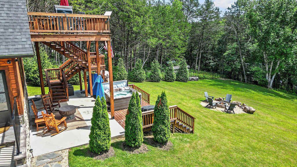 A wooden deck with a staircase leading to a covered area, surrounded by a well-maintained lawn and trees.