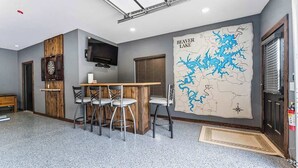 Een kamer met een barhoek, een wandtelevisie en een grote kaart van Beaver Lake aan de muur.