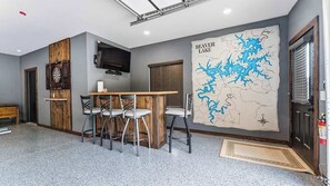 A room with a bar area, a mounted television, and a large map of Beaver Lake on the wall. - Hot Tub, Lake Front, NEW Game Rm, Fire Pit, Kayaks (Eureka Springs)
