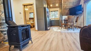 A cozy living room with a stone fireplace, wooden flooring, and a leather couch. - Hot Tub, Lake Front, NEW Game Rm, Fire Pit, Kayaks (Eureka Springs)