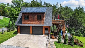 A two-story house with a garage, a deck, and a stone pathway leading to the entrance. - Hot Tub, Lake Front, NEW Game Rm, Fire Pit, Kayaks (Eureka Springs)