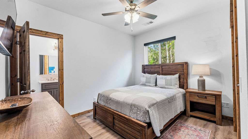 Un dormitorio con cama, mesita de noche y ventilador de techo.