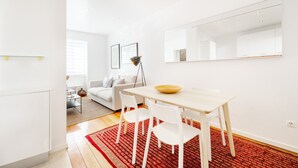 A modern living room with a dining area, white furniture, and a large mirror. - Navegantes Townhouse by Olala Homes. (Cascais)