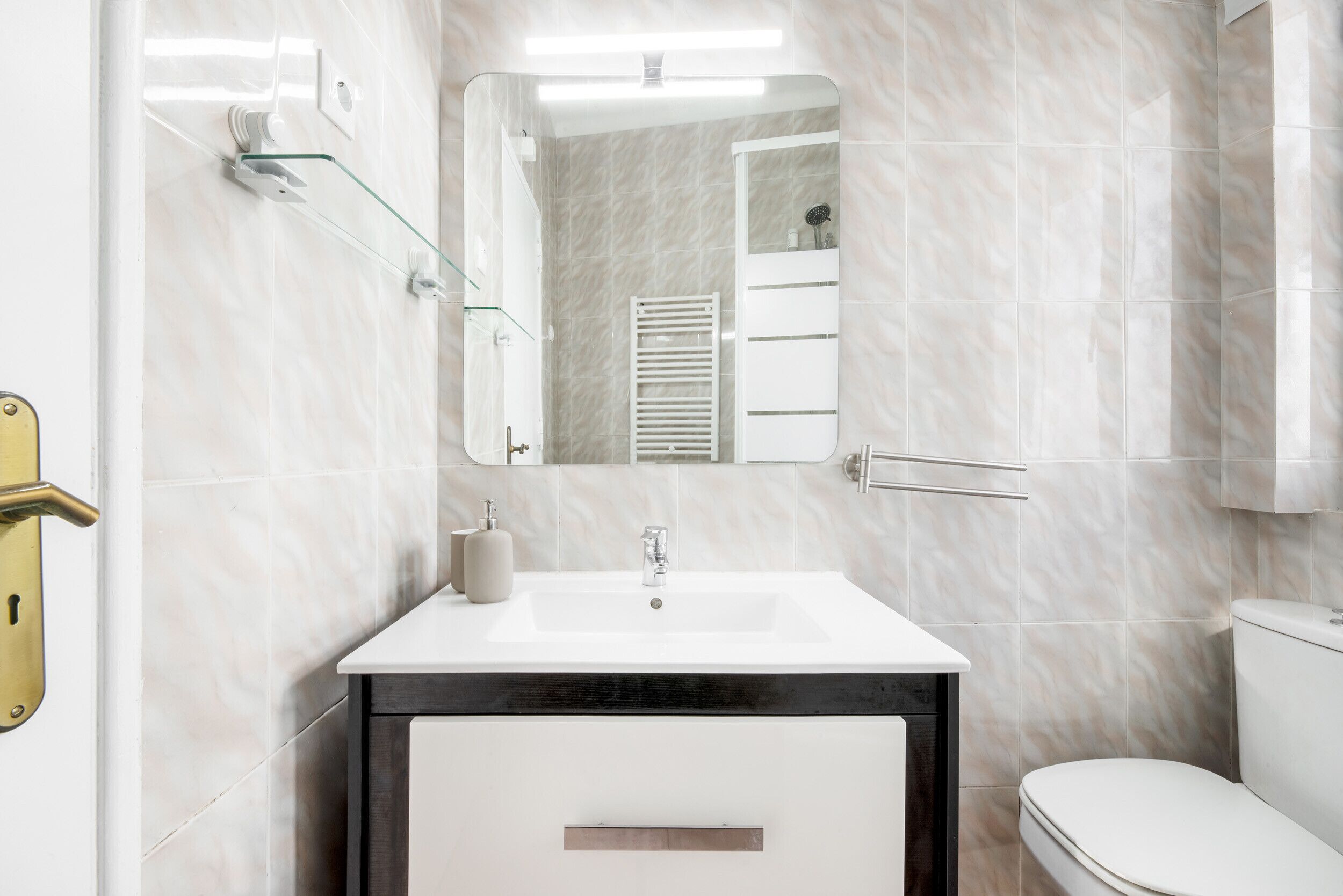 A bathroom with a white sink, mirror, and toilet.