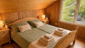 Un dormitorio con paneles de madera, una cama, mesitas de noche y una ventana con vistas.