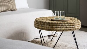 Une chambre à coucher avec un lit, un pouf en osier, un miroir et une armoire verte.