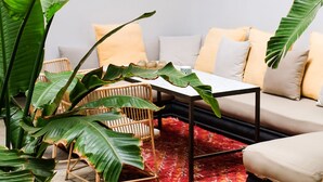 Une pièce comprenant un canapé, des fauteuils, une table et de grandes plantes vertes.