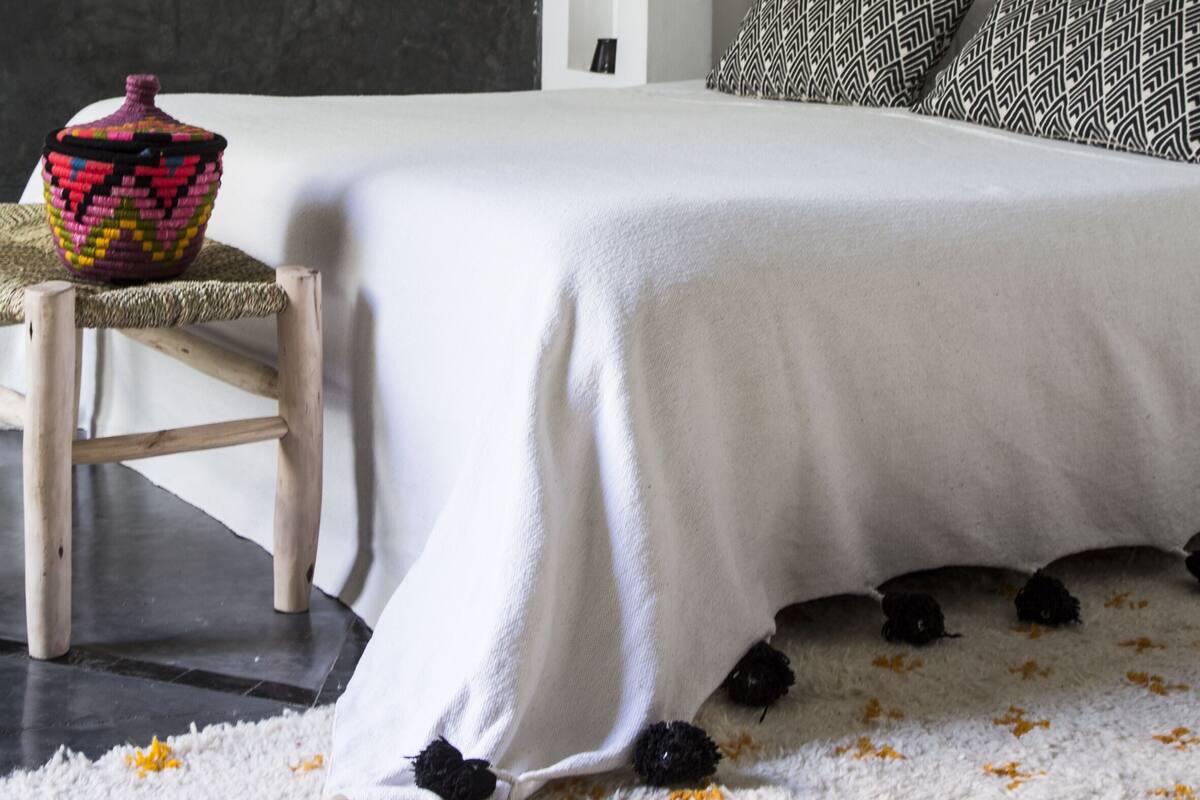 A modern bedroom with a large bed, a small side table, and a decorative basket.