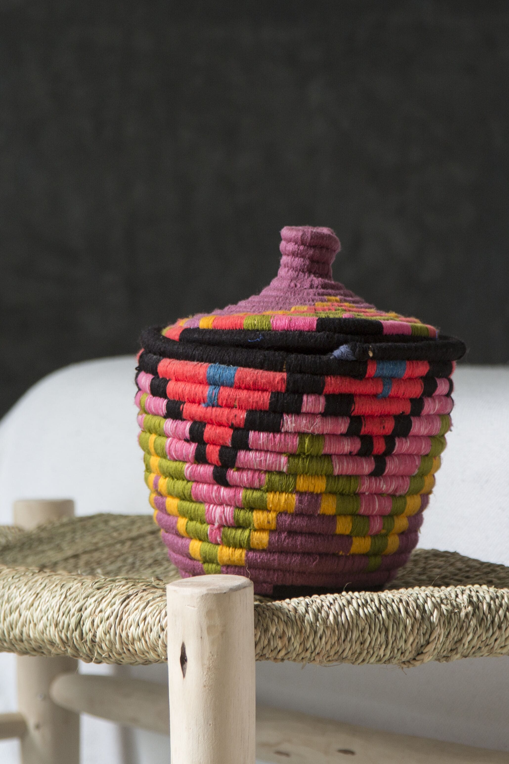 A colorful woven basket on a wooden chair.