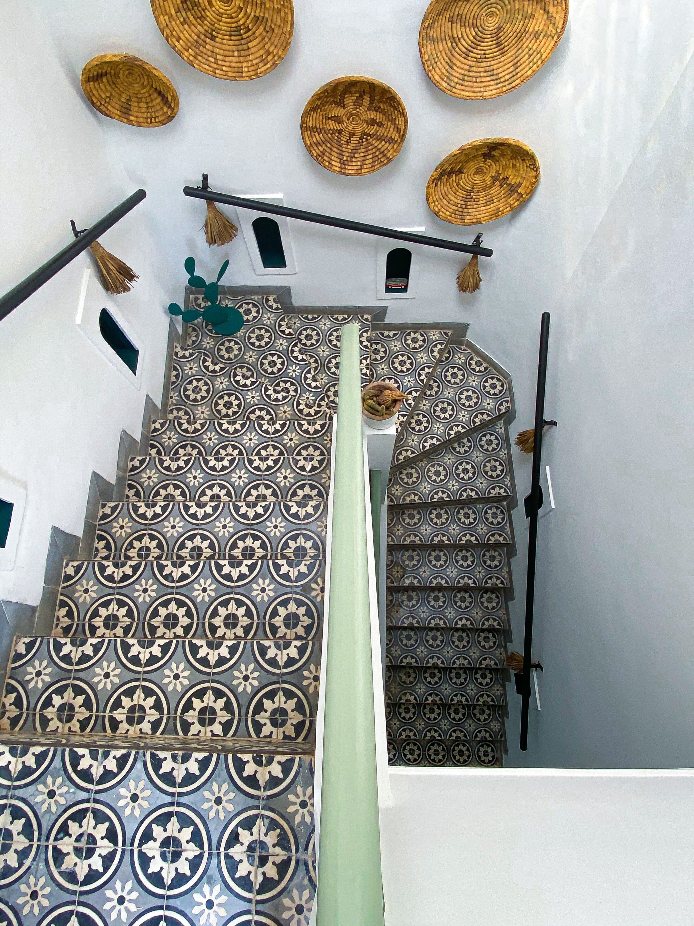 A staircase with patterned tiles, a green curtain, and hanging baskets.
