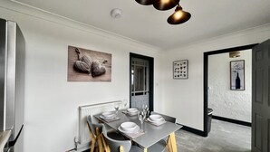 A modern dining area with a rectangular table, grey chairs, and a pendant light fixture. - Havenwood House (Nottingham)