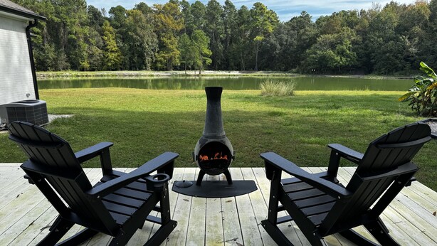 A deck with two Adirondack chairs and a wood-burning stove. - Escape to Tranquility 125 Acre Property with Trails Lake Spacious House Fire Pit (Kingsland)