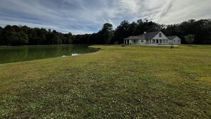 A house with a large lawn and a pond. - Escape to Tranquility 125 Acre Property with Trails Lake Spacious House Fire Pit (Kingsland)