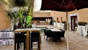 An outdoor patio with a pool, tables, chairs, and a Coca-Cola branded umbrella.