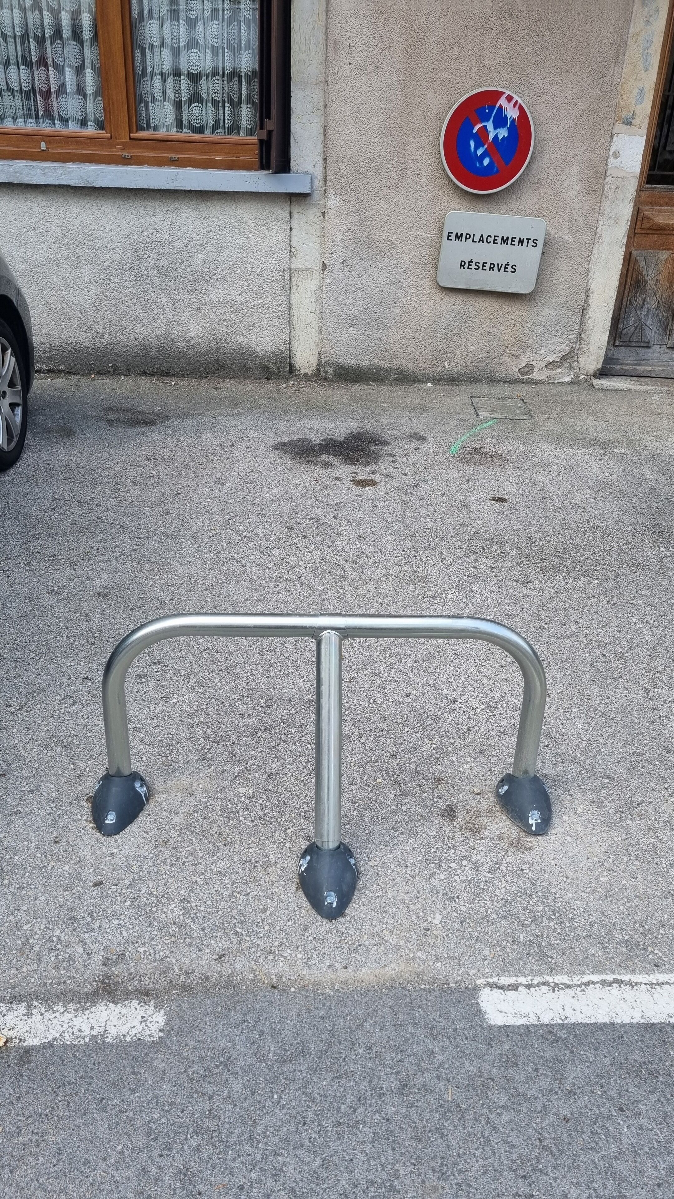 A metal barrier on a street with a 'No Parking' sign and a sign indicating 'Employment Reservations' on a building.