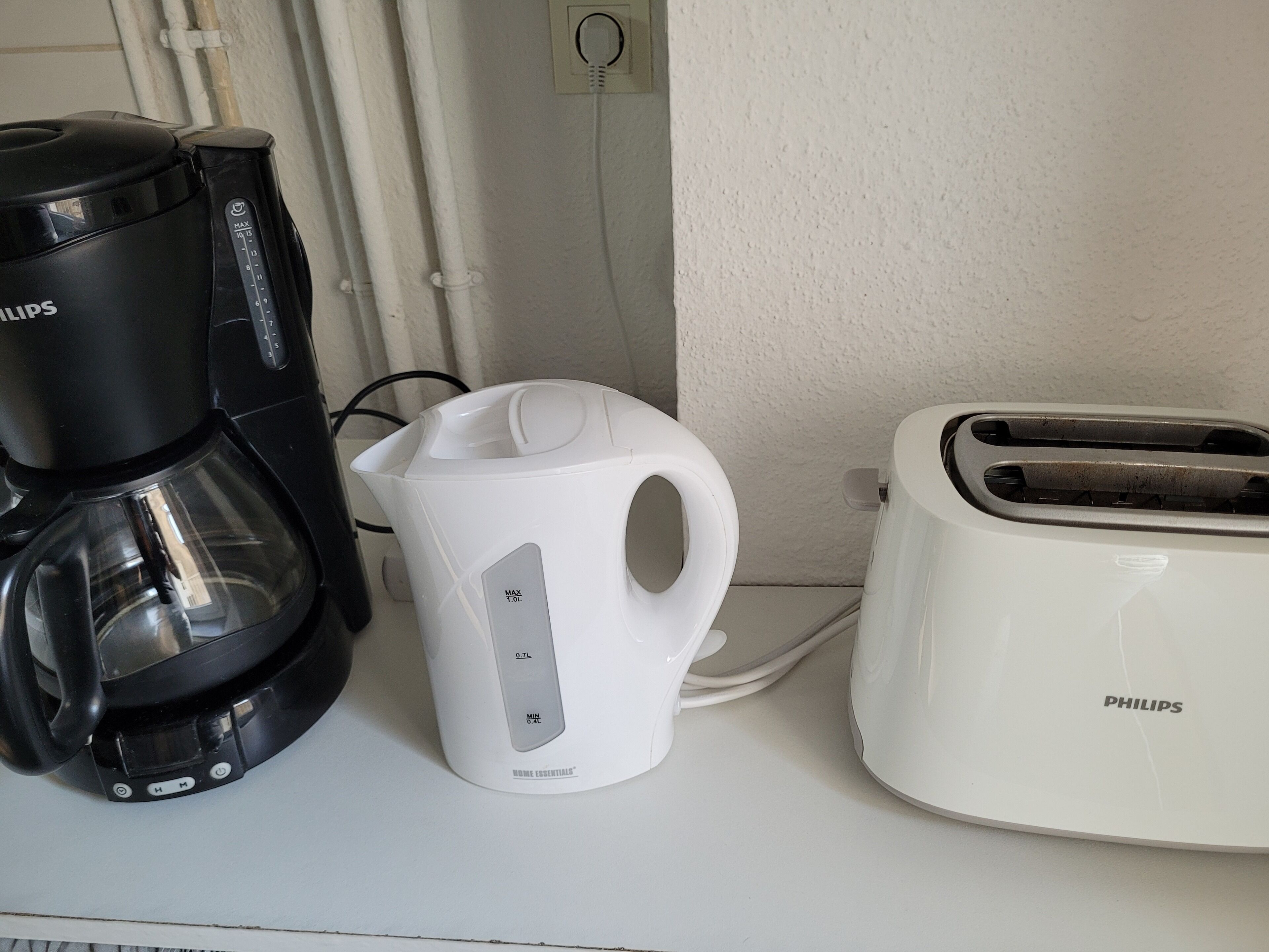 A coffee maker, a water kettle, and a toaster on a white countertop.