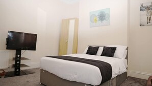 Quarto com cama, televisão e obras de arte nas paredes.