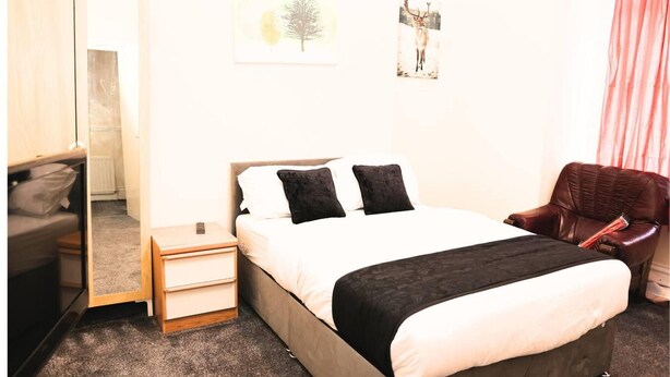 Quarto com cama, mesas de cabeceira, uma cadeira e um guarda-roupa.