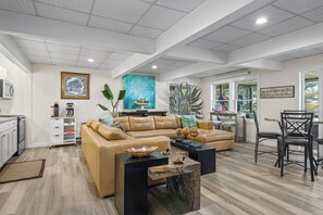 A spacious living area with a sectional sofa, a coffee table, and a dining area with chairs.