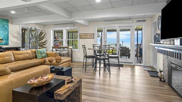A spacious living area with a leather sofa, a dining table with chairs, and a kitchen area with a stove.