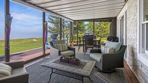 A covered patio with wicker furniture, a table with decorative items, and a view of the outdoors.