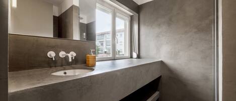 A modern bathroom with a large mirror, a sink, and a window.
