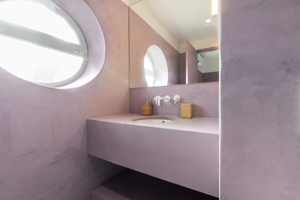 A bathroom with a round window, a sink, and a mirror.