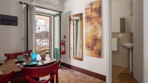 A dining area with a wooden table, red chairs, and a blue glassware set. A fire extinguisher is mounted on the wall. - Le Dimore del Corso Acireale II Sicily Stay near Catania Taormina, the Sea, Etna (Acireale)