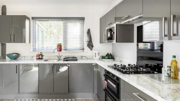 A modern kitchen with grey cabinets, a stainless steel sink, and a built-in oven. - 3 Bed House - Sleeps 5 - Parking - Garden - Wifi (Blackburn)