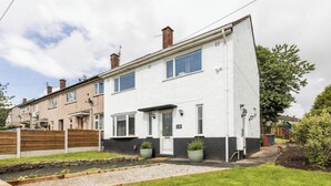 A two-story residential building with a white facade, a front door, and a number '128' on the wall. - 3 Bed House - Sleeps 5 - Parking - Garden - Wifi (Blackburn)