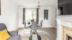 A modern living room with a dining area, a fireplace, and a view of the outdoors. - 3 Bed House - Sleeps 5 - Parking - Garden - Wifi (Blackburn)