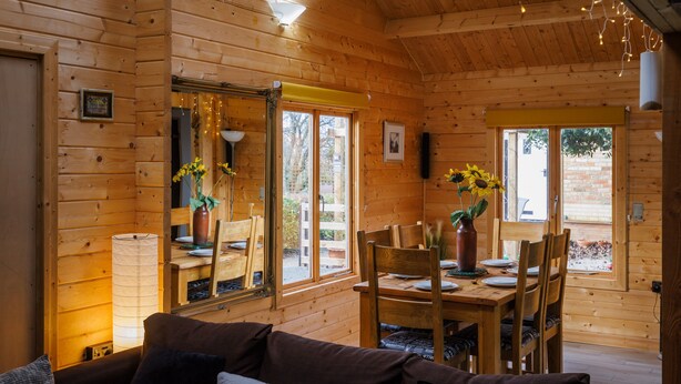 L’intérieur d’un chalet en bois comprend un coin repas, un canapé et de grandes fenêtres.