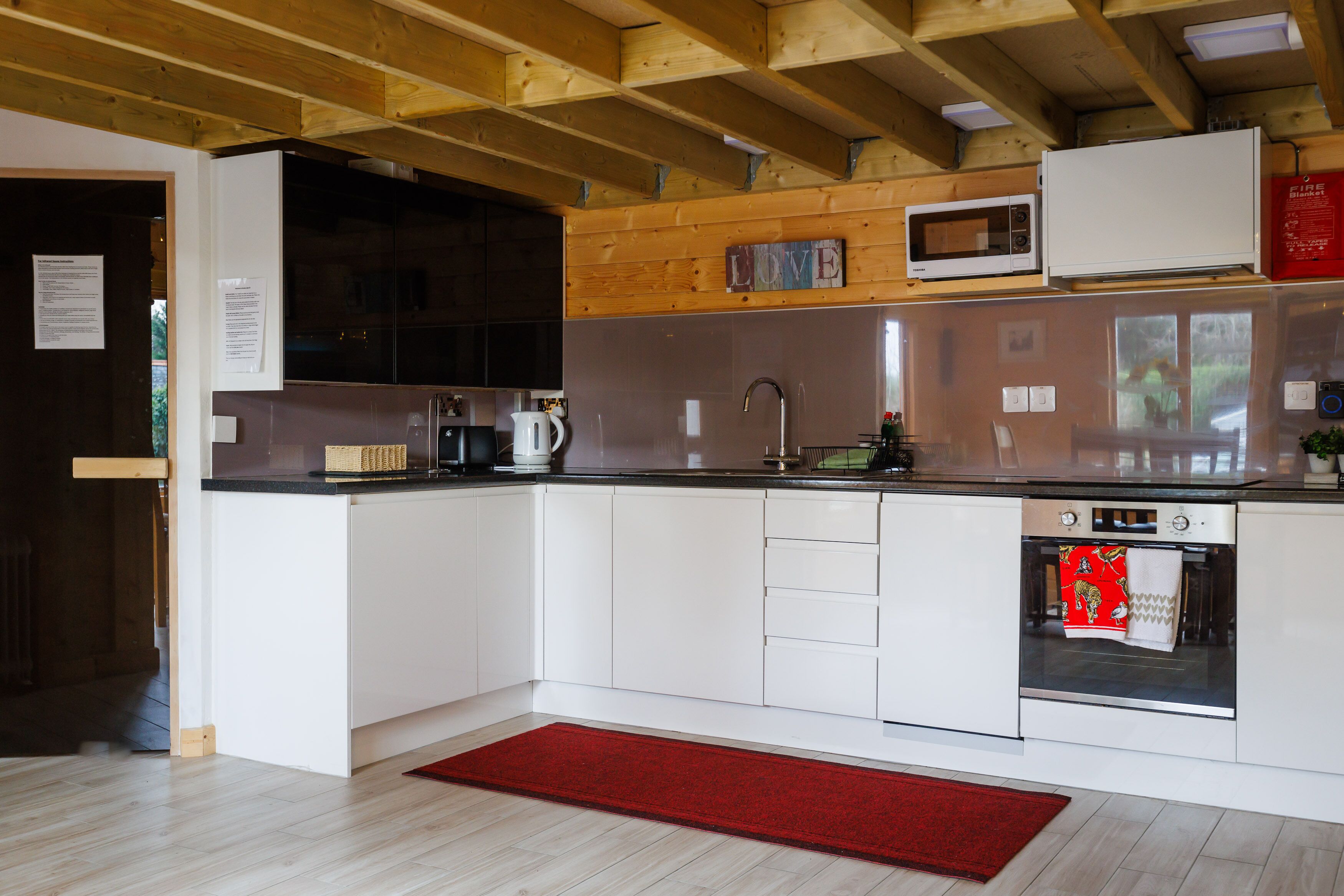 Een moderne keuken met witte kasten, een roestvrijstalen spoelbak en een rood tapijt.