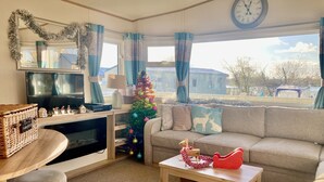 Una sala de estar acogedora con televisor, árbol de Navidad, sofá y mesa de centro.