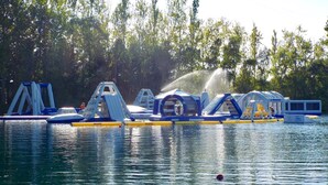 Parque acuático al aire libre con estructuras inflables y un tobogán de agua.
