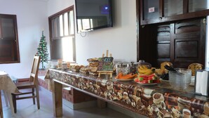 A breakfast buffet with various food items and a small Christmas tree. - Pousada Kasarão Praia Grande (Ubatuba)
