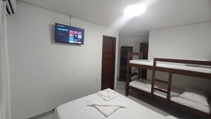 A room with bunk beds, a flat-screen TV mounted on the wall, and a door leading to another room. - Pousada Kasarão Praia Grande (Ubatuba)