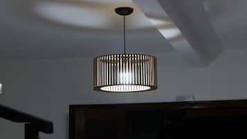 Un luminaire suspendu de forme cylindrique, doté de lamelles verticales.