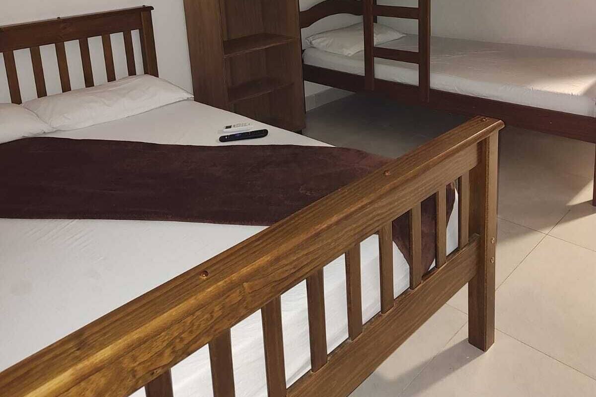 A dormitory room with bunk beds and a wooden wardrobe.