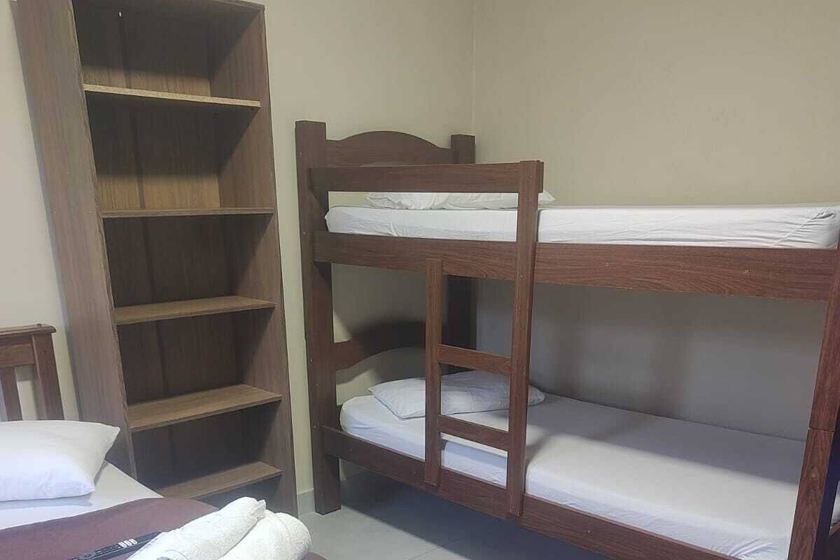 A bunk bed room with a wooden desk and a wardrobe.