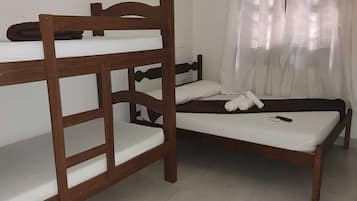 A bunk bed room with a wooden headboard, a single bed, and a small wooden table.