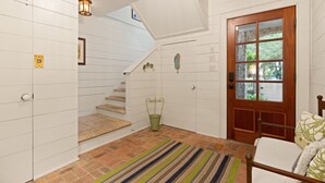 A staircase with a green bucket, a wooden door with glass panels, and a striped rug. - Gated Seaside Community sleeps 10, private courtyard pool & community pool (St Simons Island)