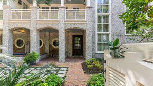 A building with a covered patio area, stone columns, and a brick pathway. - Gated Seaside Community sleeps 10, private courtyard pool & community pool (St Simons Island)