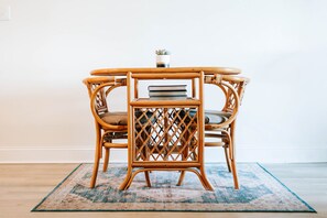 Une table ronde en bois, dotée d’un dossier ajouré et de chaises rembourrées, posée sur un tapis à motifs.