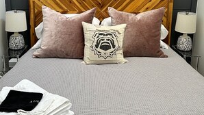 Un lit avec une tête de lit en bois, plusieurs oreillers et une serviette blanche pliée.