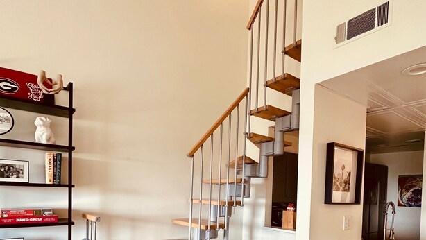 Un salon moderne avec un escalier en bois, un canapé en cuir et une bibliothèque.