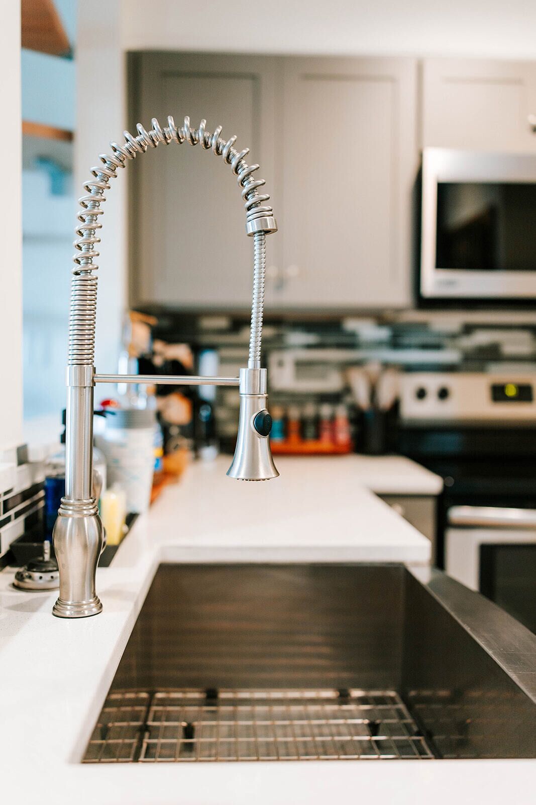 Een keuken met een moderne kraan, een roestvrijstalen spoelbak en een magnetron op de achtergrond.